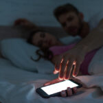 vrouw in bed met telefoon in de hand in slaap gevallen