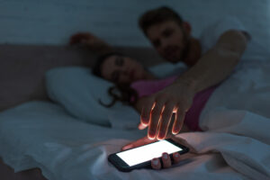 vrouw in bed met telefoon in de hand in slaap gevallen
