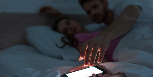 vrouw in bed met telefoon in de hand in slaap gevallen